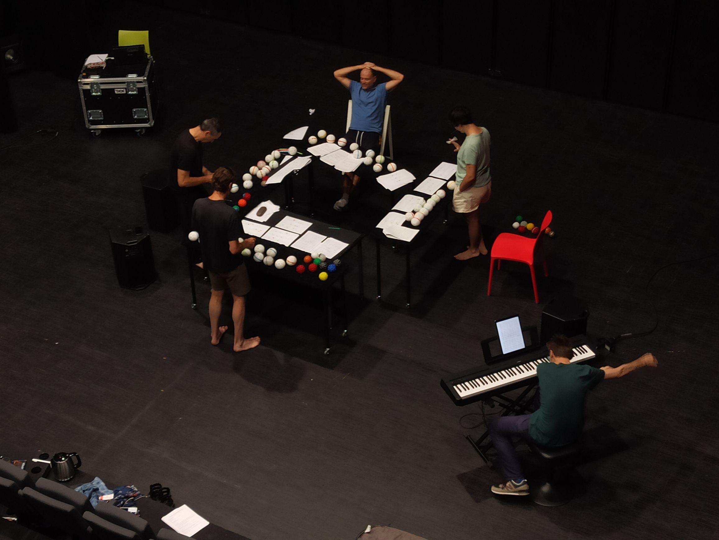 Session d’entraînement de Concerto pour quatre jongleurs et un piano. De nombreuses balles (et donc notes) sont disposées devant les jongleurs sur la table.